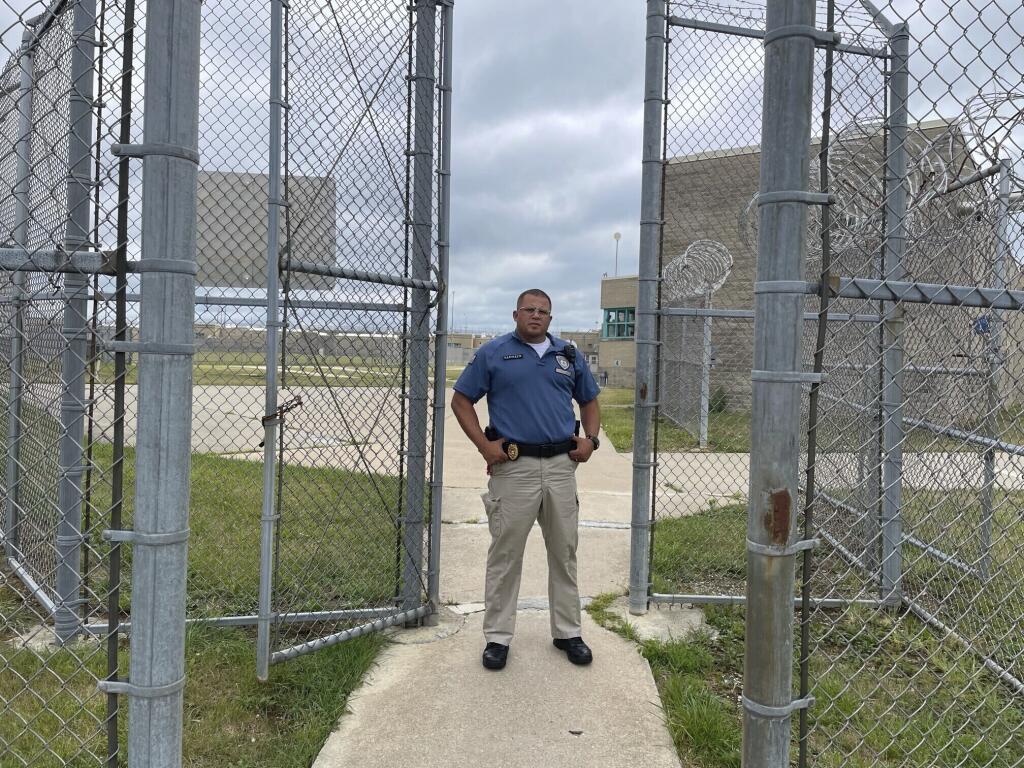 Maj. Albin Narvaez stands in the gated entryway to the prison yard at the Fulton Reception and Diagnostic Center, Thursday, July 13, 2023, in Fulton, Missouri. Narvaez, who is chief of custody at the prison, said applications for correctional officers have increased since the state implemented a pay raise this spring. (AP Photo/David A. Lieb)