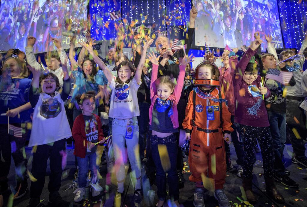 In this photo provided by NASA, New Horizons principal investigator Alan Stern, of the Southwest Research Institute in Boulder, Colo., center, celebrates with school children at the exact moment that the New Horizons spacecraft made the closest approach of Kuiper Belt object Ultima Thule, early Tuesday, Jan. 1, 2019, at Johns Hopkins University Applied Physics Laboratory in Laurel, Md. (Bill Ingalls/NASA via AP)