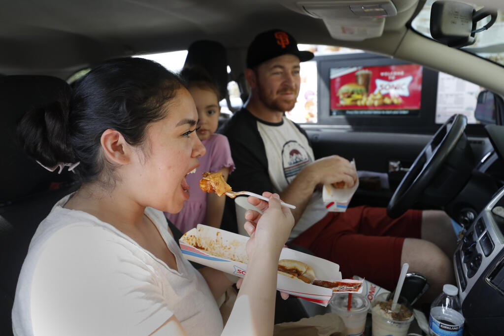 Sonic Drive-In fans Suri Newman, her husband Dale, their daughter Zoe, 3, center, and son Ezra, 5, not pictured, eat lunch Thursday at the newly opened Sonic Drive-In on Santa Rosa Avenue in Santa Rosa.(The Press Democrat)