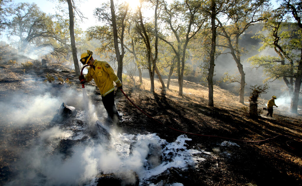 Hopland's Cal Fire personnel Alan Molina, left, and Carignane Ferreira mop up hot spots during the Lyons fire near Sutter Lakeside Hospital in Lakeport, Tuesday, Oct. 13, 2020. The fire threatened several homes in the area.  (Kent Porter / The Press Democrat) 2020