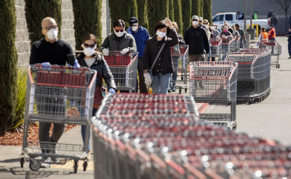 Shoppers wait in line spaced 6 feet apart at the Santa Rosa Costco on Friday, April 3, 2020. The line stretched around the building, and patrons waited up to 45 minutes to enter the store as personnel controlled the total number of people in the store at one time. (John Burgess/The Press Democrat)