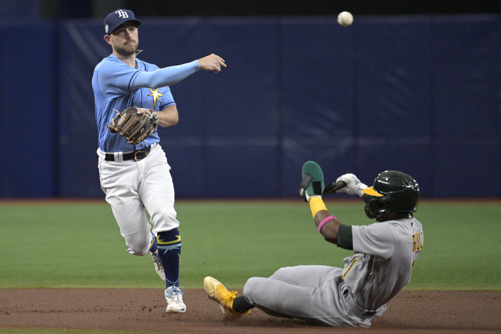Tampa Bay Rays second baseman Brandon Lowe, left, throws to first base to complete a double play after forcing out A’s runner Esteury Ruiz during the first inning Saturday in St. Petersburg, Florida. (Phelan M. Ebenhack / ASSOCIATED PRESS)