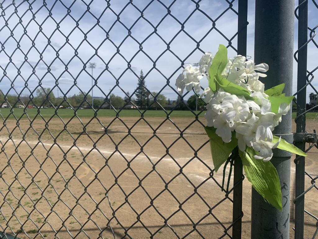 Flowers tucked into fencing April 4, 2022 serve as a makeshift memorial for a man shot and killed at Northwest Community Park on April 2, 2022. (Press Democrat Staff)