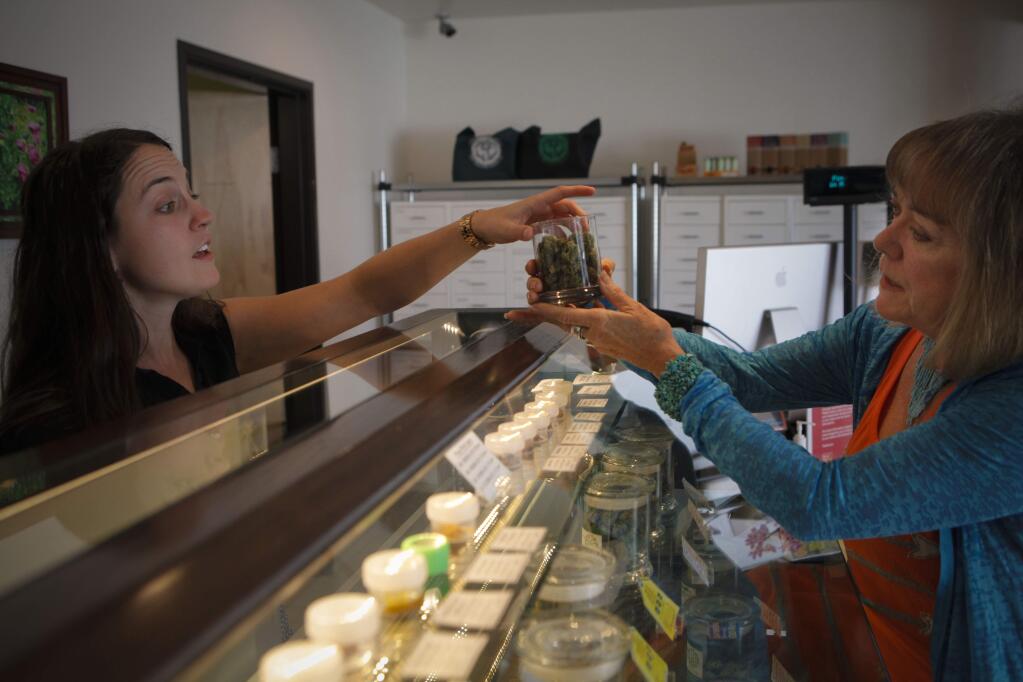 Petaluma, CA, USA. Tuesday, July 26, 2016._ Ashley Nelson, the Operations Manager at Peace in Medicine in Santa Rosa lets Linda Stokely of Petaluma get a whiff of some of the buds that they sell. Stockely, 66, who is very physically active says that the medical marijuana which she uses as salves or edibles or in a vaporizer do not give her the bad side effects she got from prescription medication. (CRISSY PASCUAL/ARGUS-COURIER STAFF)