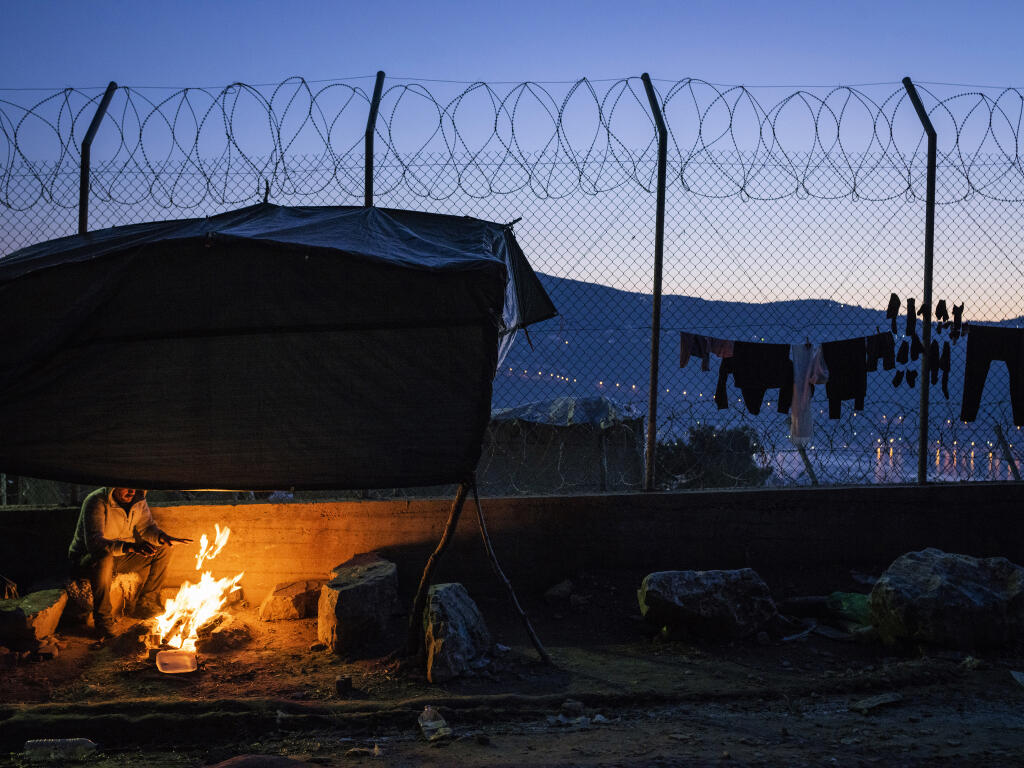 An asylum-seeker from Syria tries to stay warm as he prepares dinner for his family in the tent city in Samos, Greece. (LAURA BOUSHNAK / New York Times)