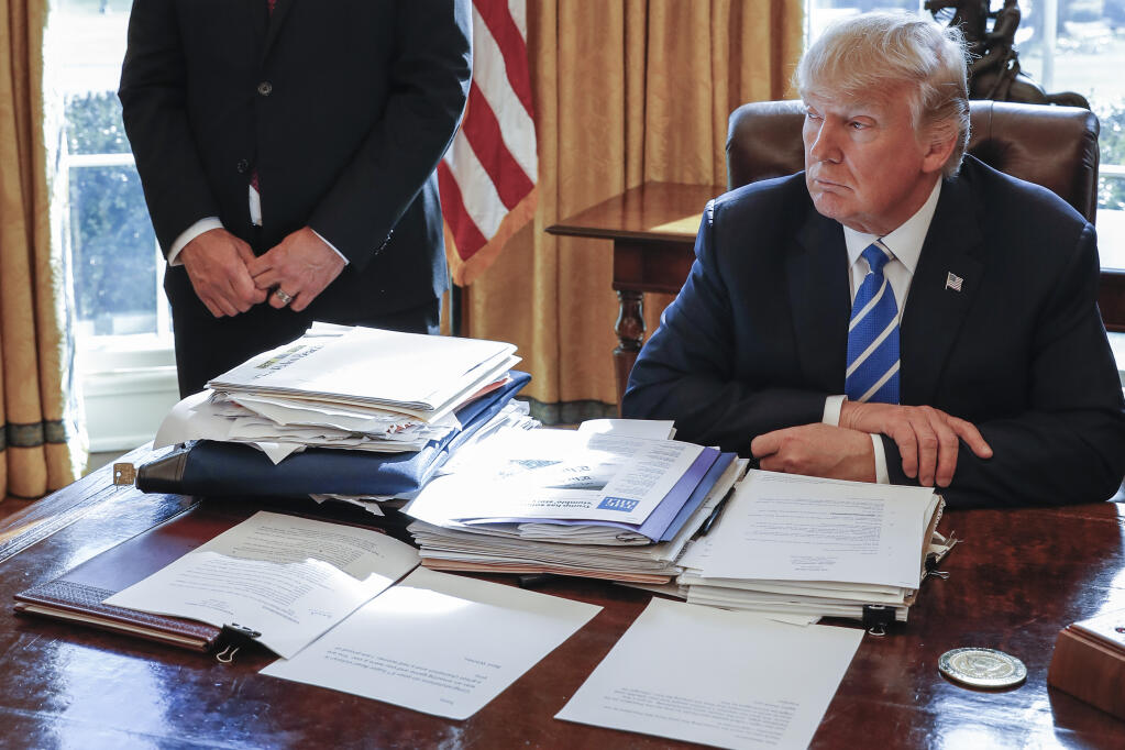 President Donald Trump sits at his desk after a meeting with Intel CEO Brian Krzanich in the Oval Office of the White House in Washington, Feb. 8, 2017, as a classified documents lockbag is visible on the desk at left, with the key still inside. (AP Photo/Pablo Martinez Monsivais, File)