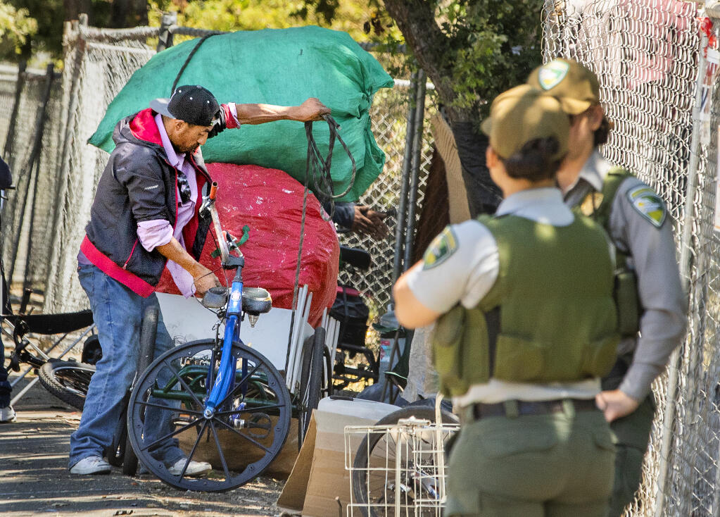 A homeless man uses rope to tie down his possessions as he prepares to leave the Joe Rodota Trail encampment in Santa Rosa July 25, 2022. (John Burgess/Sonoma Magazine)