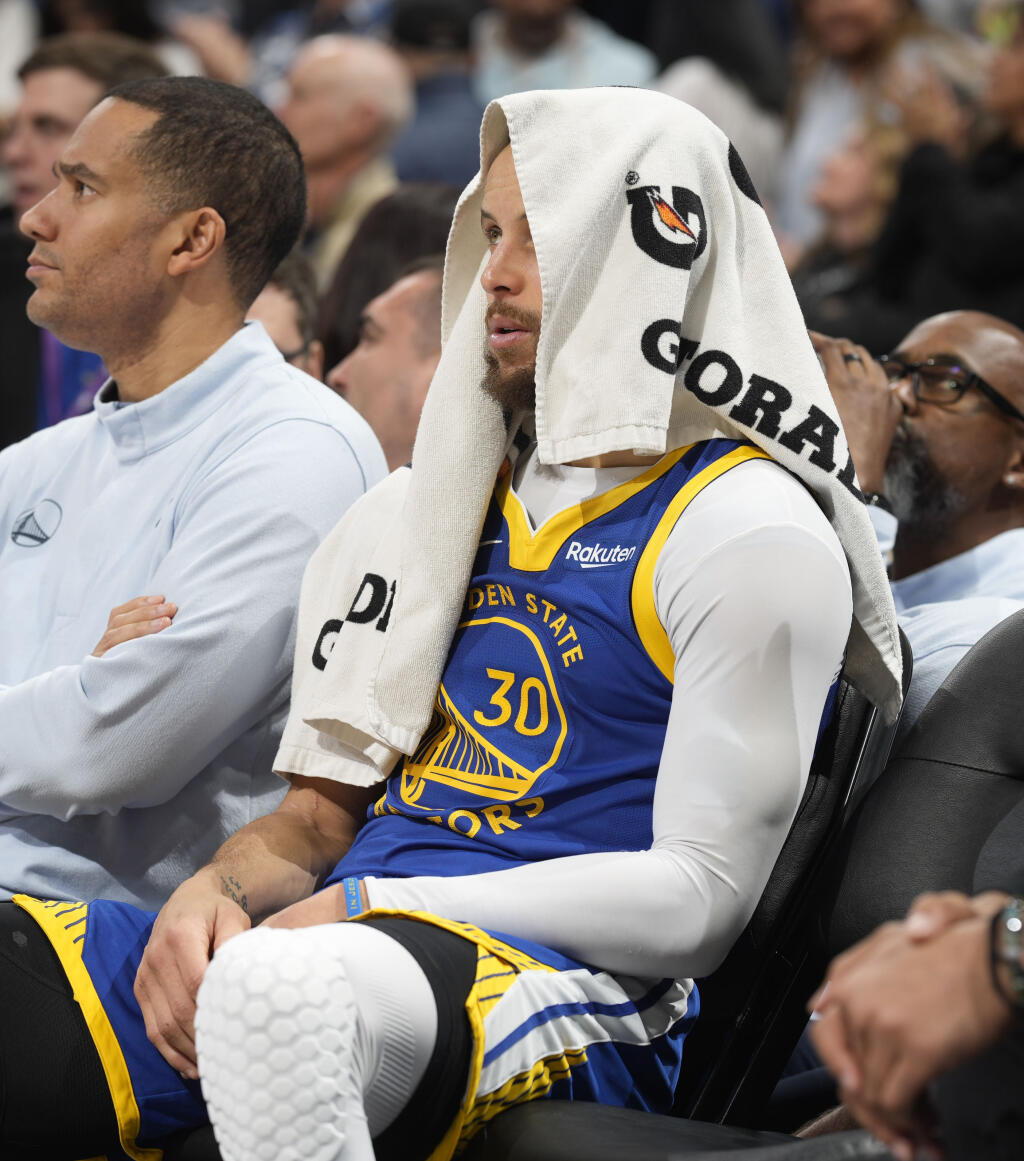 Warriors guard Stephen Curry sits on the bench with a towel over his head as time runs out in the second half Thursday against the Nuggets in Denver. (David Zalubowski / ASSOCIATED PRESS)