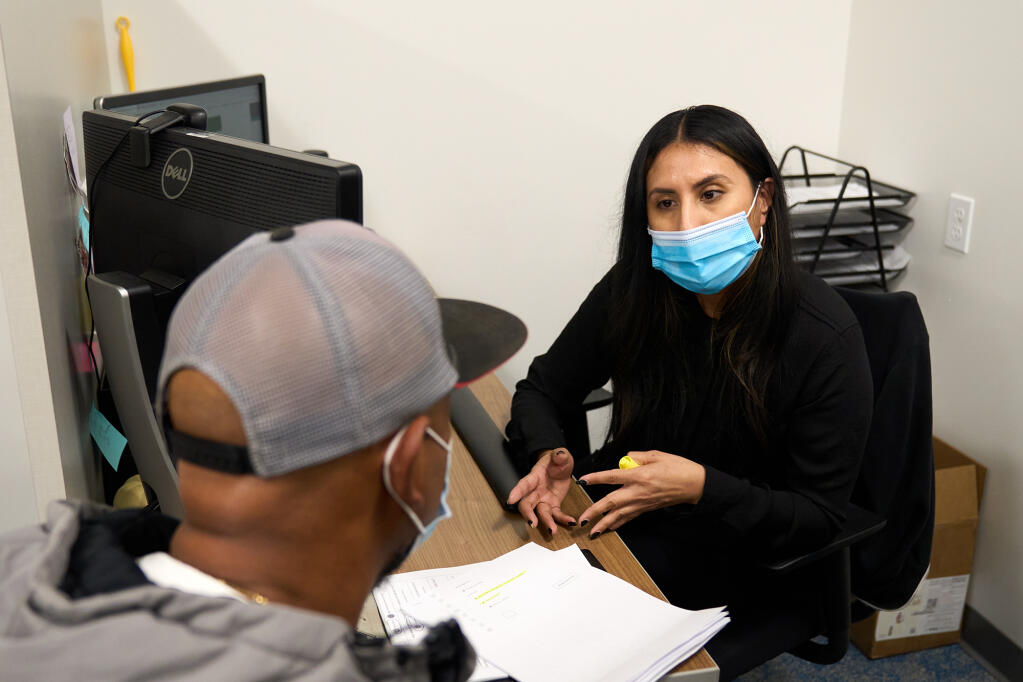 Benefits counselor Perla Lopez assists an undocumented adult at St. John’s Community Health in Los Angeles on Dec. 19, 2023. Undocumented adult will become eligible for Medi-Cal health care coverage in the new year. Photo by Lauren Justice for CalMatters