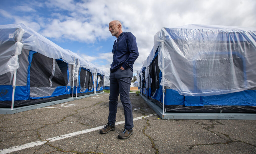 Sonoma County Homelessness Services Division Director Dave Kiff makes the rounds through unoccupied tents while getting them ready for incoming guests at the safe place to sleep tent camp at the Sonoma County government complex parking lot at Administration Drive and Paulin Drive in Santa Rosa, Wednesday, March 22, 2023. (Chad Surmick / The Press Democrat)
