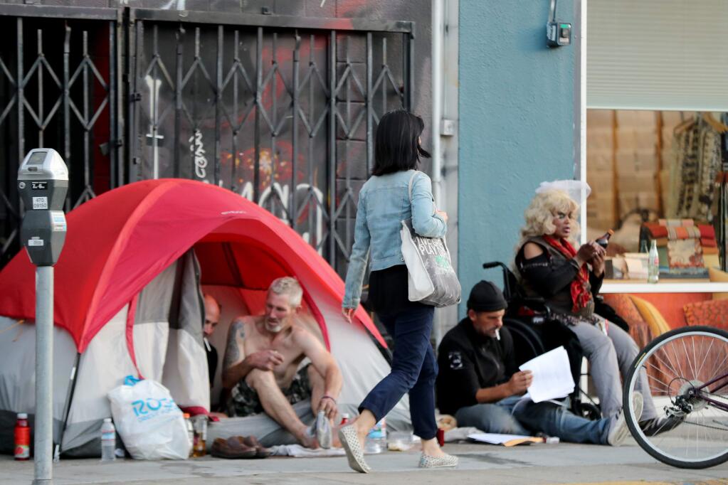 A pedestrian walks past a homeless encampment on Howard Street in San Francisco. (RAY CHAVEZ / Bay Area News Group, 2018)