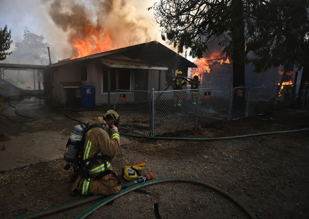 A Cal Fire firefighter puts on an air pack before helping to contain fires that burned five homes in Clearlake Oaks, Sunday, July 18. 2021.  (Kent Porter / The Press Democrat)