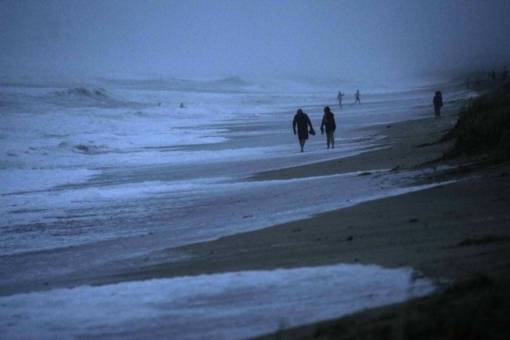 FILE - People walk along the oceanfront at Jensen Beach Park, where waves were reaching the dune's edge as conditions deteriorated with the approach of Hurricane Nicole, Nov. 9, 2022, in Jensen Beach, Fla. After months of gradually warming sea surface temperatures in the tropical Pacific Ocean, NOAA officially issued an El Nino advisory Thursday, June 8, 2023, and stated that this one might be different than the others. (AP Photo/Rebecca Blackwell, File)