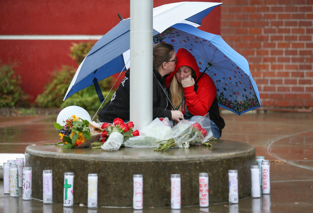 Carole Snell, left, comforts Misty Lenwell, mother of Jayden Pienta, as they visit a memorial at the flagpole in front of Montgomery High School in Santa Rosa, Friday, March 1, 2024.  (Christopher Chung / The Press Democrat)