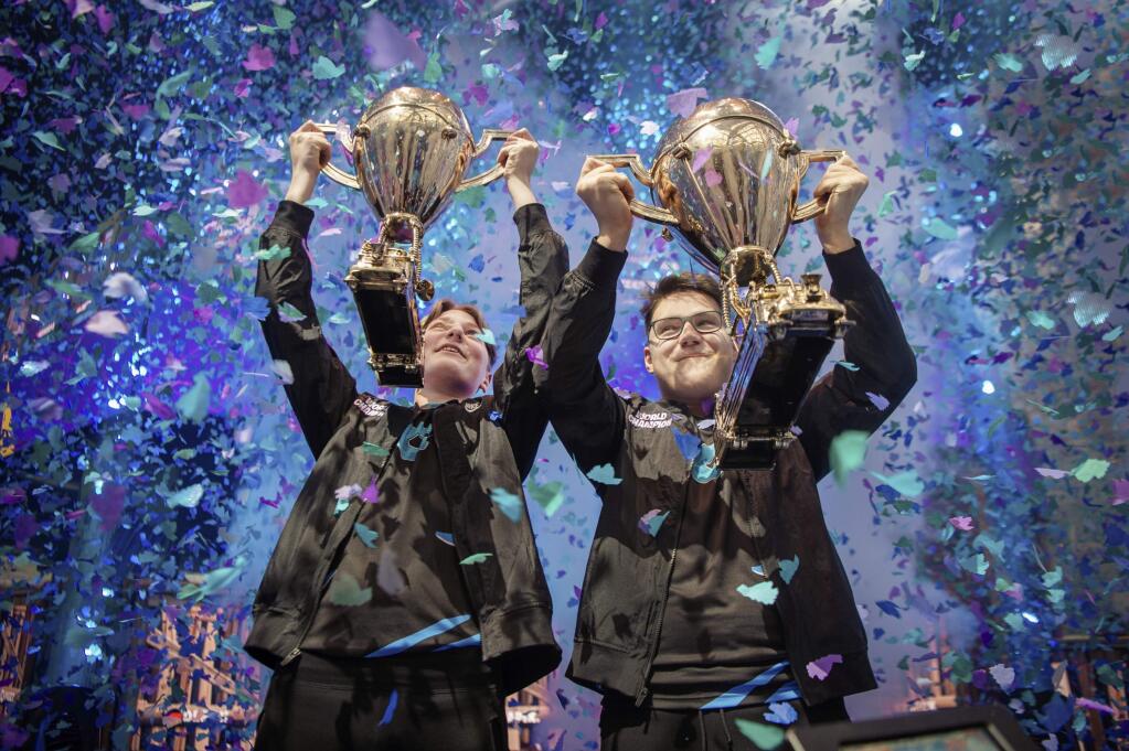 In this Saturday, July 27, 2019 photo, provided by Epic Games, Emil 'Nyhrox' Bergquist Pedersen, of Norway, left, and David 'Aqua' Wang, of Austria, hold up their trophies after winning the Fortnite World Cup duo championship in New York. (Epic Games via AP)
