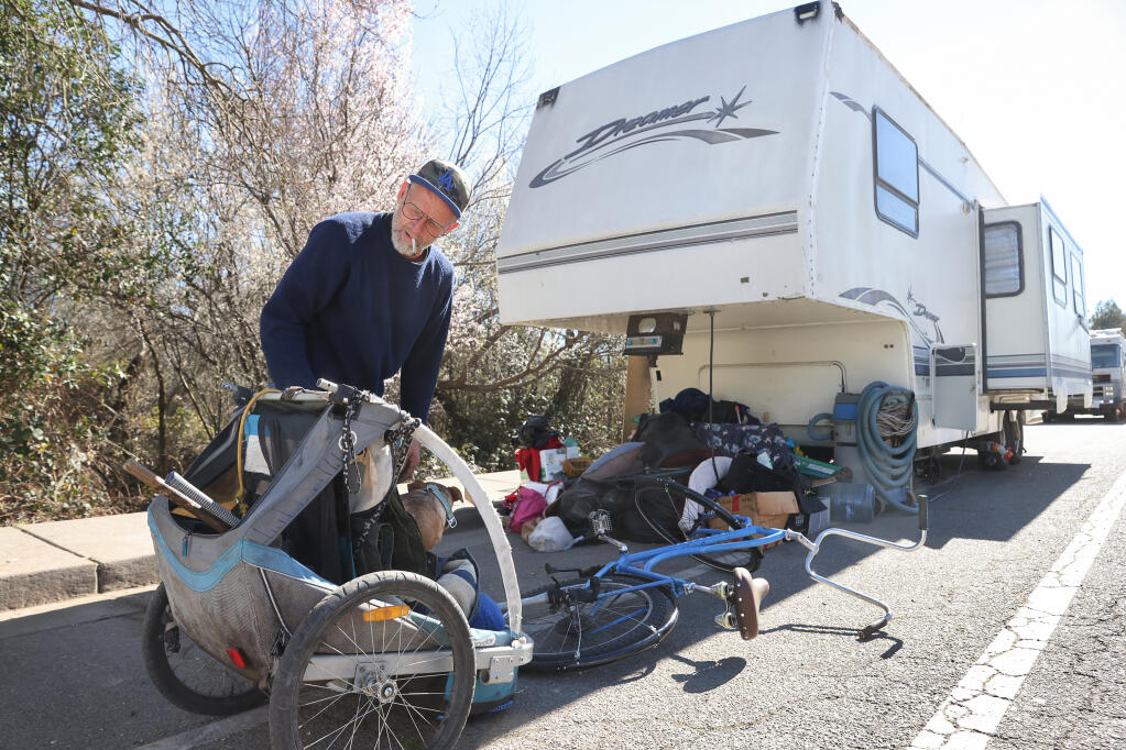 John Henry Hull gets his dog ready for a bike ride along Morris Street, where he's been living in a trailer in Sebastopol on Wednesday, February 16, 2022. Hull will soon be moving to the RV village along Gravenstein Highway North in Sebastopol. (Christopher Chung/ The Press Democrat)