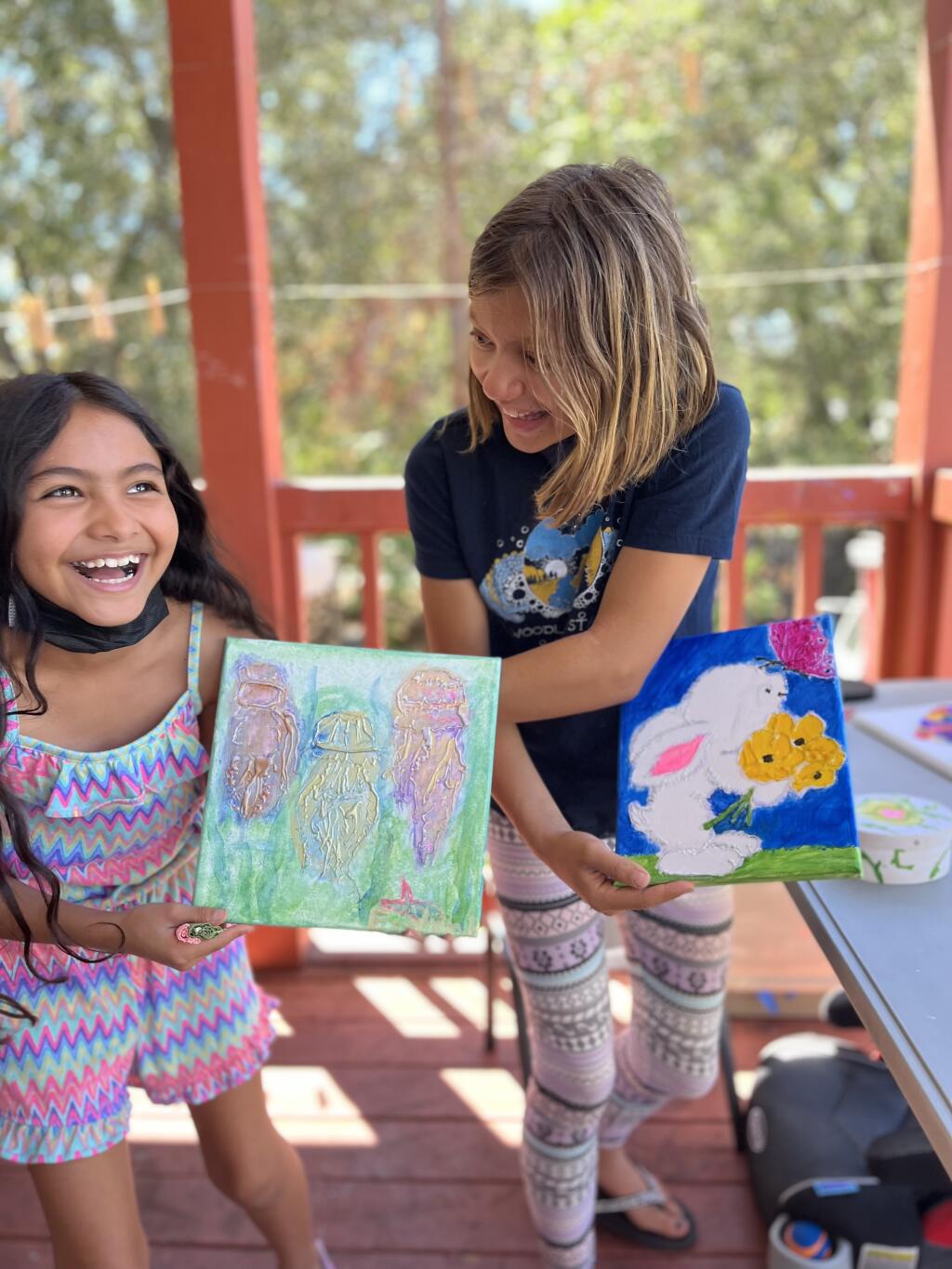 Two young girls smile at the creation the painting they made during one of Art Escape’s Summer Camps last year. With limited capacity, the camps fill up quickly as soon as registration opens in March. (Submitted)