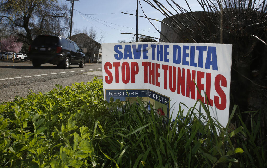 FILE – A sign opposing a plan to build a giant tunnel to ship water to Southern California is displayed near Freeport, California, on May 2, 2016. California Gov. Gavin Newsom has a plan to speed up some construction projects throughout the state. But some lawmakers and environmental advocates fear his plan would benefit the tunnel project, which they oppose. (AP Photo/Rich Pedroncelli, file)