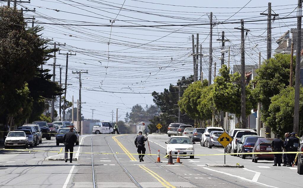 San Francisco Police officers walk along San Jose Avenue where a boy was struck and killed by a light-rail train as he ran across a street in San Francisco, Tuesday, May 12, 2015. (AP Photo/Jeff Chiu)