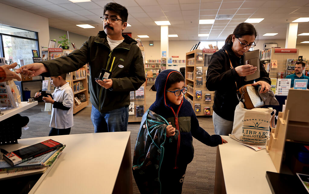 Christian Hernandez and son Aiden, 6, left, and Araceli Dominguez with her son, Julio, 6, use their library card to check out books at the Roseland Regional Library in Santa Rosa, Wednesday, Jan. 10, 2024. (Kent Porter / The Press Democrat)