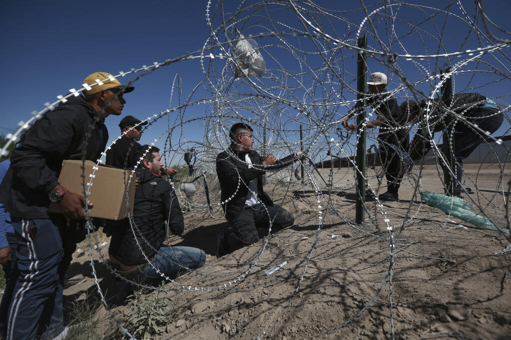 Migrants cross a barbed-wire barrier into the United States from Ciudad Juarez, Mexico, Tuesday, May 9, 2023. The U.S. is preparing for the Thursday, May 11th end of the Title 42 policy, linked to the coronavirus pandemic that allowed it to quickly expel many migrants seeking asylum. (AP Photo/Christian Chavez)
