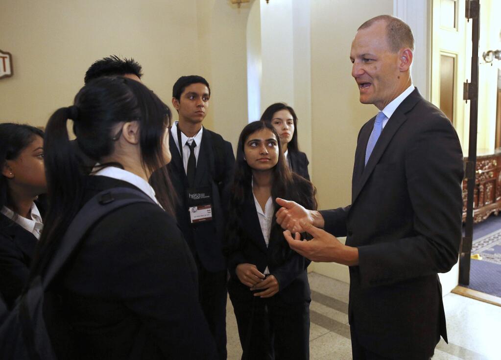 Assemblyman Kevin McCarty, D-Sacramento, right, talks with a group of high school students after his news conference concerning a proposed package of bills dealing with the recent college admissions scandal, Thursday, March 28, 2019, in Sacramento, Calif. McCarty, and other Democratic lawmakers unveiled a half-dozen measures that would require that three college administrators sign off on special admissions and a ban upon preferential admissions for students related to the institution's donors of alumni. (AP Photo/Rich Pedroncelli)