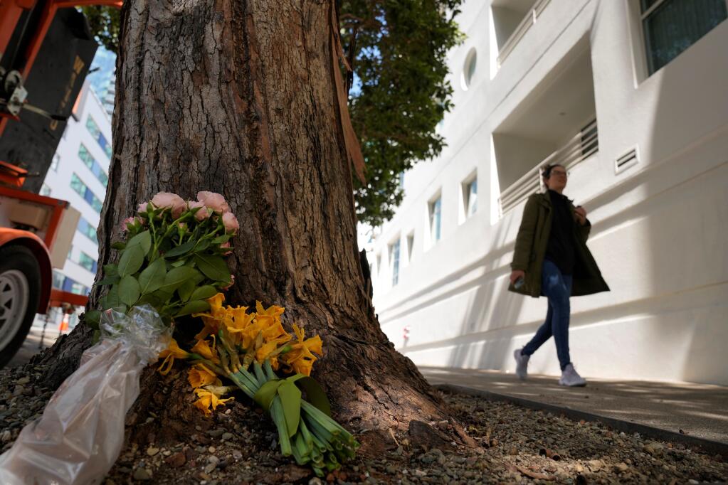 A woman walks past flowers left outside an apartment building where a technology executive was fatally stabbed in San Francisco, Wednesday, April 5, 2023. Bob Lee, a technology executive who created Cash App and was currently chief product officer of MobileCoin, was fatally stabbed in San Francisco early Tuesday, April 4, 2023, according to the cryptocurrency platform and police. (AP Photo/Eric Risberg)