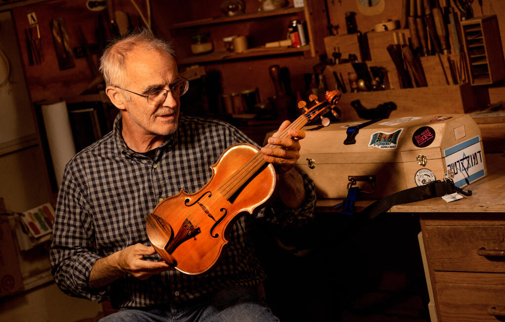 Santa Rosa violin maker Andrew Carruthers with his latest retirement project, Violinabox,  in his Santa Rosa workshop, Tuesday, June 6, 2023. The violin was sequentially built by 10 violin makers around the world, each shipping it in a box to the next craftsman. (John Burgess / The Press Democrat)