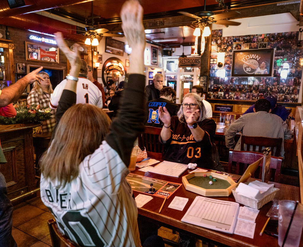 Laura Baker celebrates rolling a home run while playing Strat-O-Matic baseball with Lea Davis on opening day of the season at Ausiello’s Fifth Street Bar and Grill in Santa Rosa, Tuesday, Jan. 3, 2024. (John Burgess / The Press Democrat)