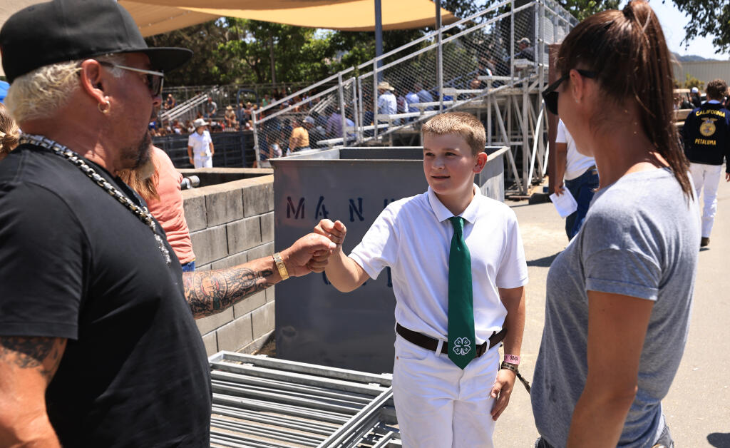 Guy Fieri greets  Jaxon Trappe, 10, after Fieri bought one of Trappe’s pigs during the Junior Livestock Auction at the Sonoma County Fair in Santa Rosa, Saturday, Aug. 5, 2023. The Food Network star and longtime Sonoma County resident is donating the pig to Redwood Gospel Mission and the Salvation Army in Santa Rosa. (Kent Porter / The Press Democrat)