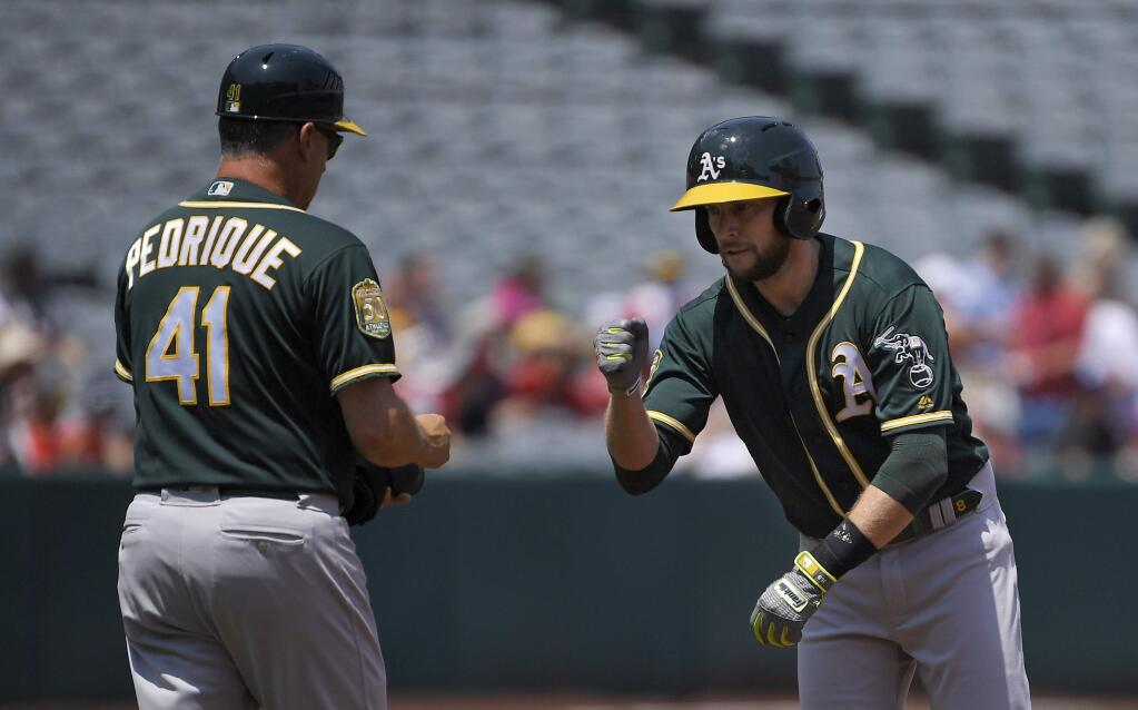Oakland Athletics' Jed Lowrie, right, is congratulated by first base coach Al Pedrique after hitting a double for his 1,000th career hit during the first inning of a baseball game against the Los Angeles Angels, Sunday, Aug. 12, 2018, in Anaheim, Calif. (AP Photo/Mark J. Terrill)