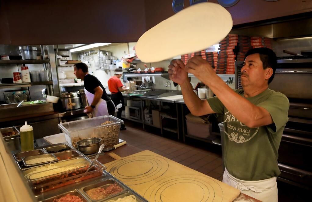 Mario Medina tosses a pizza during the evening rush at Mary's Pizza on Summerfield Road in Santa Rosa, Monday, Sept. 23, 2019. (Kent Porter / The Press Democrat file)