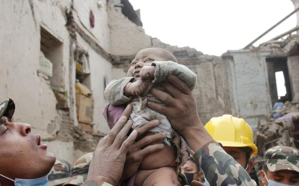 In this Sunday, April 26, 2015, photo taken by Amul Thapa and provided by KathmanduToday.com, four-month-old baby boy Sonit Awal is held up by Nepalese Army soldiers after being rescued from the rubble of his house in Bhaktapur, Nepal, after Saturday's 7.8-magnitude earthquake shook the densely populated Kathmandu valley. Thapa says that when he saw the baby alive after 20 hours of rescue efforts  all my sorrow went. Everyone was clapping. It gave me energy and made me smile in spite of lots of pain hidden inside me.' (Amul Thapa/KathmanduToday.com via AP)