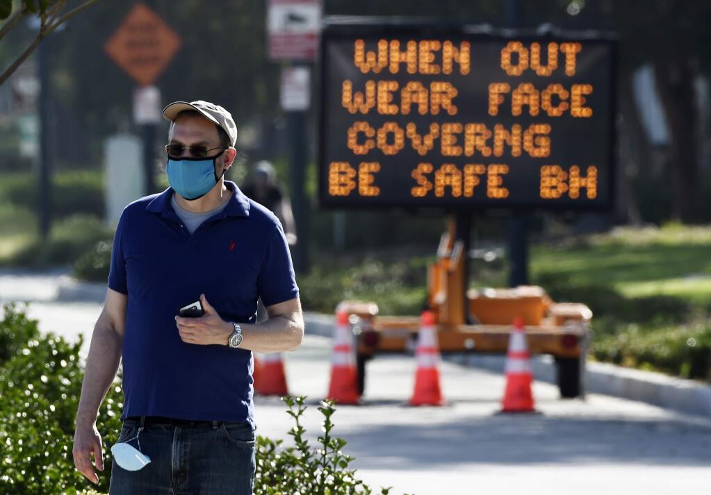 FILE - In this April 16, 2020, file photo, an electronic sign on Santa Monica Boulevard reminds people to wear masks to limit the spread of coronavirus in Beverly Hills, Calif. Gov. Gavin Newsom's administration on Thursday, June 18, 2020, mandated that Californians wear masks in most indoor settings as the state continues to battle the coronavirus. (AP Photo/Chris Pizzello, File)