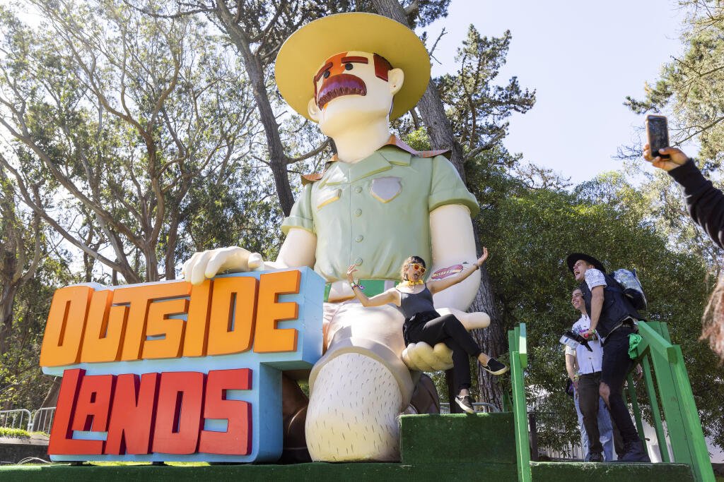 A woman takes a photo with the Ranger Dave statue during the first day of the Outside Lands Music Festival at Golden Gate Park in San Francisco, Friday, Aug. 5, 2022. (Jessica Christian/San Francisco Chronicle via AP)