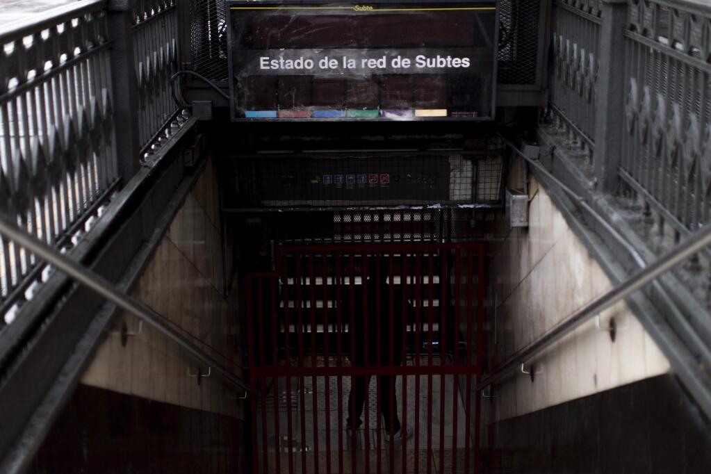 A subway employee stands in the closed entrance of the Buenos Aires's subway during a blackout, in Buenos Aires, Argentina, Sunday, June 16, 2019. Argentina and Uruguay were working frantically to return power on Sunday, after a massive power failure left large swaths of the South American countries in the dark. (AP Photo/Tomas F. Cuesta)