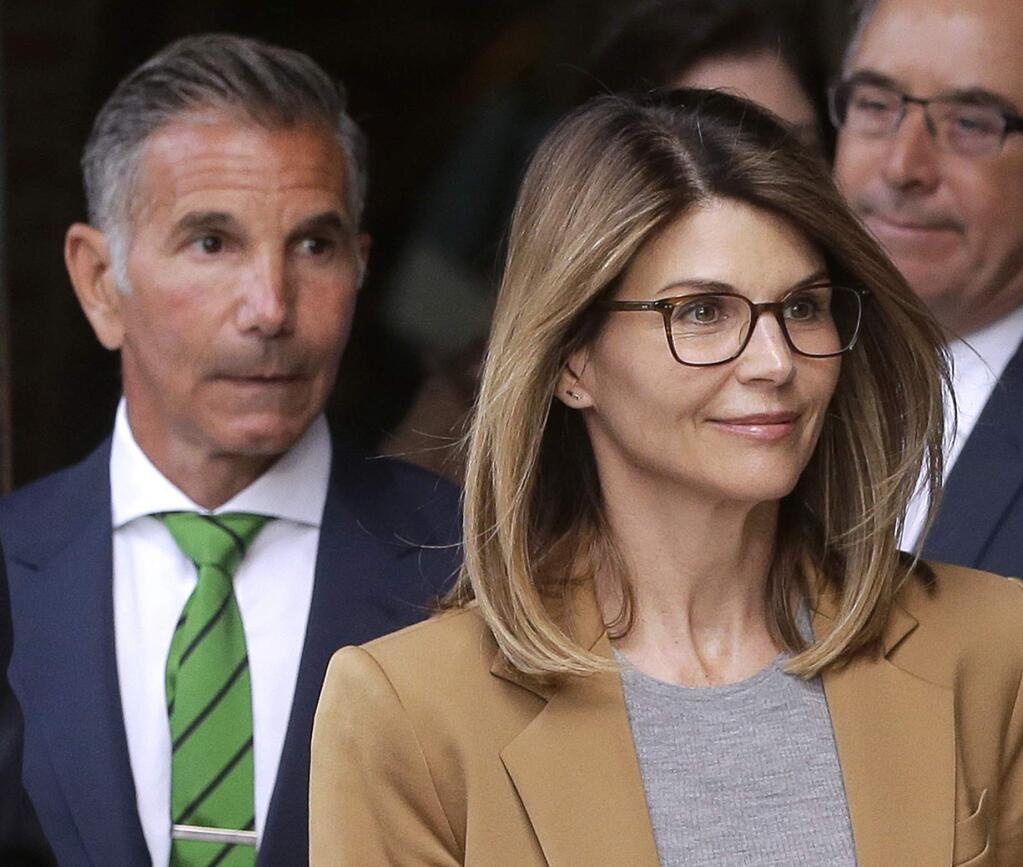 FILE - In this April 3, 2019 file photo, actress Lori Loughlin, front, and husband, clothing designer Mossimo Giannulli, left, depart federal court in Boston after facing charges in a nationwide college admissions bribery scandal. On Tuesday, April 9, Loughlin and Giannulli were among 16 prominent parents indicted on an additional charge of money laundering conspiracy in the case. (AP Photo/Steven Senne, File)