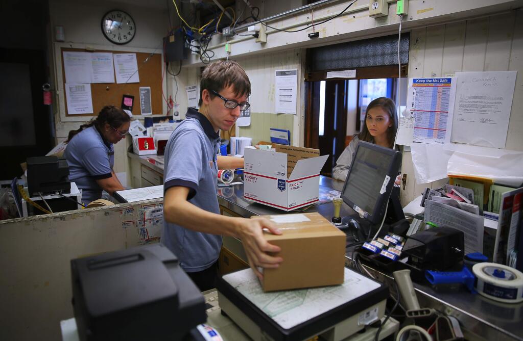 Postal worker Andrew Evans helps Taylor Olson send a package at the US Post Office in Sebastopol, on Monday, December 14, 2015. (Christopher Chung/ The Press Democrat)