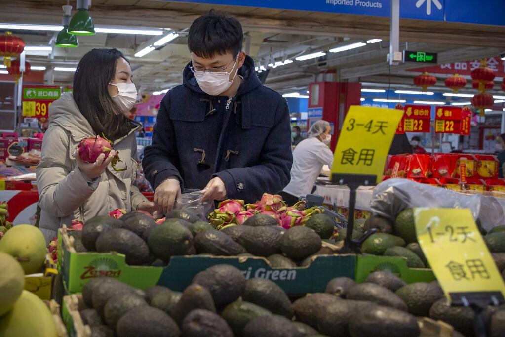 People wear face masks as they shop at a grocery store in Beijing, Saturday, Feb. 1, 2020. China's death toll from a new virus rose to 259 on Saturday and a World Health Organization official said other governments need to prepare for'domestic outbreak control' if the disease spreads in their countries. (AP Photo/Mark Schiefelbein)
