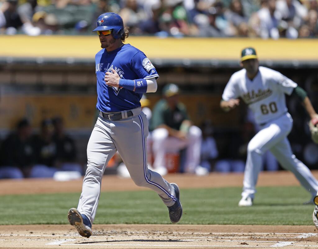 Toronto Blue Jays' Josh Donaldson, left, scores on an error in the first inning of a baseball game against the Oakland Athletics, Sunday, July 17, 2016, in Oakland, Calif. (AP Photo/Ben Margot)