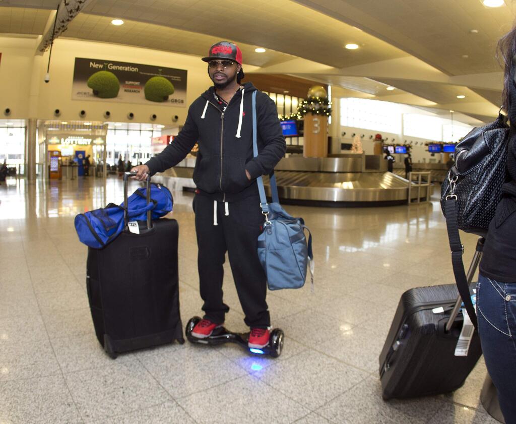 Airline passenger Gary Hammond rides on a hoverboard after claiming his luggage at Hartsfield Jackson Atlanta International Airport Friday, Dec. 11, 2015, in Atlanta. The three largest U.S. airlines are banning hoverboards because of the potential fire danger from the lithium-ion batteries that power the devices. Delta Air Lines, American Airlines and United Airlines said Thursday they are banning hoverboards in checked or carry-on luggage. JetBlue Airways has already prohibited them. (AP Photo/John Bazemore)