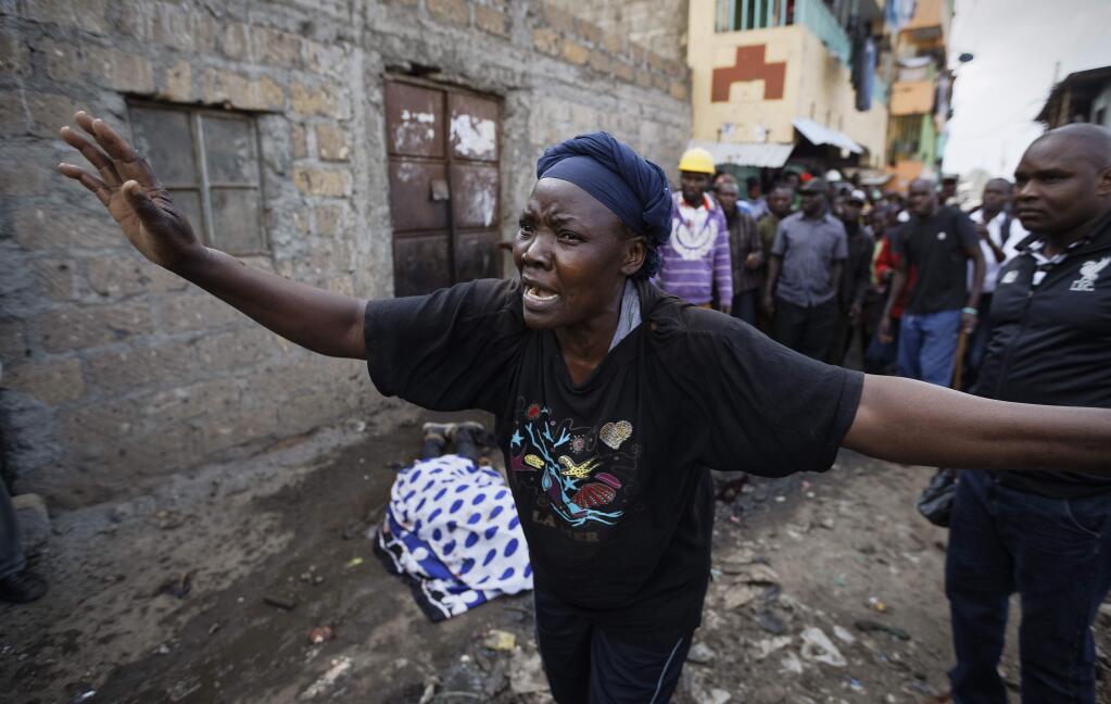 A woman wails in front of the covered body of a man who had been shot in the head and who the crowd claimed had been shot by police, as the angry crowd shouts towards the police, in the Mathare slum of Nairobi, Kenya Wednesday, Aug. 9, 2017. Kenya's election took an ominous turn on Wednesday as violent protests erupted in the capital. (AP Photo/Ben Curtis)