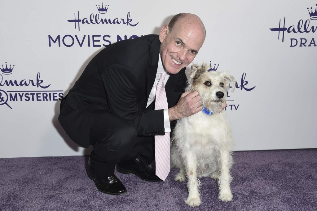 FILE - This July 26, 2018 file photo shows Bill Abbott, left, with a dog named Happy at Hallmark's Evening Gala during the TCA Summer Press Tour in Beverly Hills, Calif. The head of Hallmark's media business is leaving the company after 11 years. No reason was given for Bill Abbott's departure as CEO of Crown Media Family Networks, and no replacement was immediately named. (Photo by Richard Shotwell/Invision/AP, File)