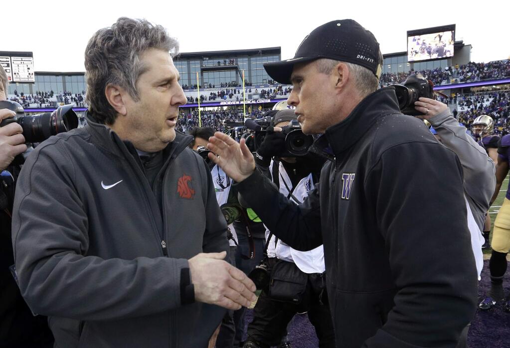 In this Nov. 27, 2015, file photo, Washington State coach Mike Leach, left, is greeted by Washington coach Chris Petersen after a game in Seattle. Rarely have both teams entered the Apple Cup with so much at stake. (AP Photo/Elaine Thompson, File)