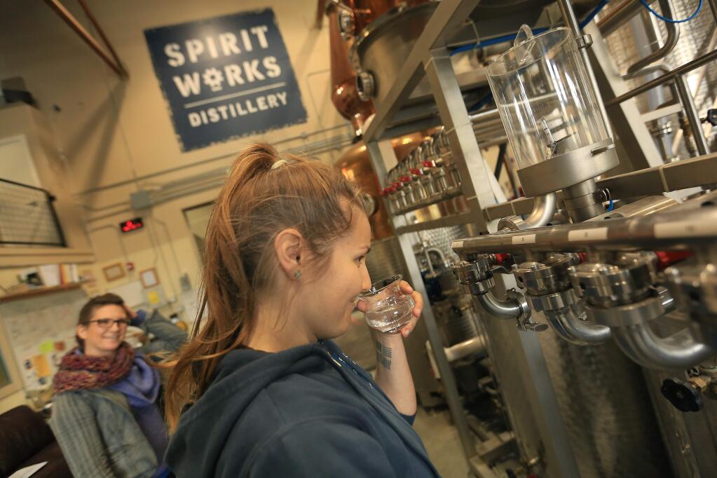 Lauren Patz smells the byproduct of distilling rye whiskey, methanol, as Kriztina Lazar laughs Wednesday at Spirit Works Distillery in Sebastopol. (Kent Porter / Press Democrat)