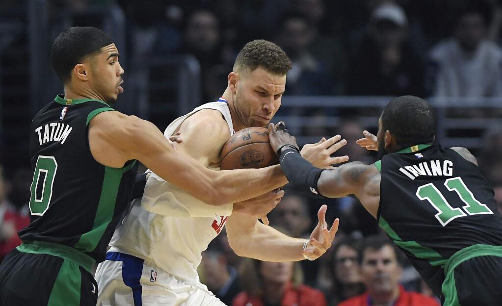 Boston Celtics forward Jayson Tatum, left, and guard Kyrie Irving, right, reach in on Los Angeles Clippers forward Blake Griffin during the first half Wednesday, Jan. 24, 2018, in Los Angeles. (AP Photo/Mark J. Terrill)