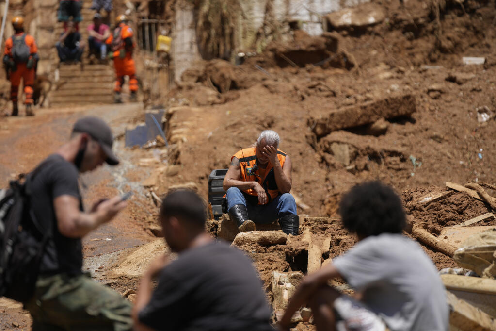 A rescue worker takes a break on the second day of rescue efforts after deadly mudslides in Petropolis, Brazil, Thursday, Feb. 17, 2022. Deadly floods and mudslides swept away homes and cars, but even as families prepared to bury their dead, it was unclear how many bodies remained trapped in the mud. (AP Photo/Silvia Izquierdo)