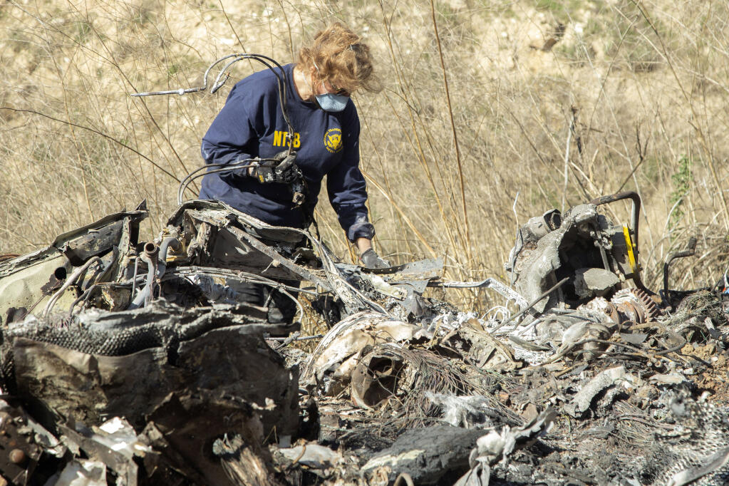 FILE - In this Jan. 27, 2020 file photo released by the National Transportation Safety Board, NTSB investigator Carol Hogan examines wreckage as part of the NTSB's investigation of a helicopter crash near Calabasas, Calif., that killed former NBA basketball player Kobe Bryant, his 13-year-old daughter, Gianna, and seven others. (James Anderson/National Transportation Safety Board via AP, File)