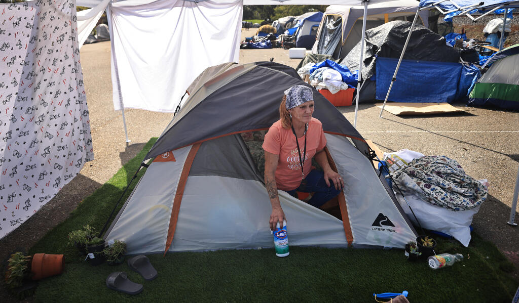 Kristi Fleming pauses as she cleans her encampment at the Park and Ride lot on Roberts Lake Road in Rohnert Park, Thursday, Sept. 9, 2021.  Those camped in the lot have to vacate by Friday morning.  (Kent Porter / The Press Democrat) 2021