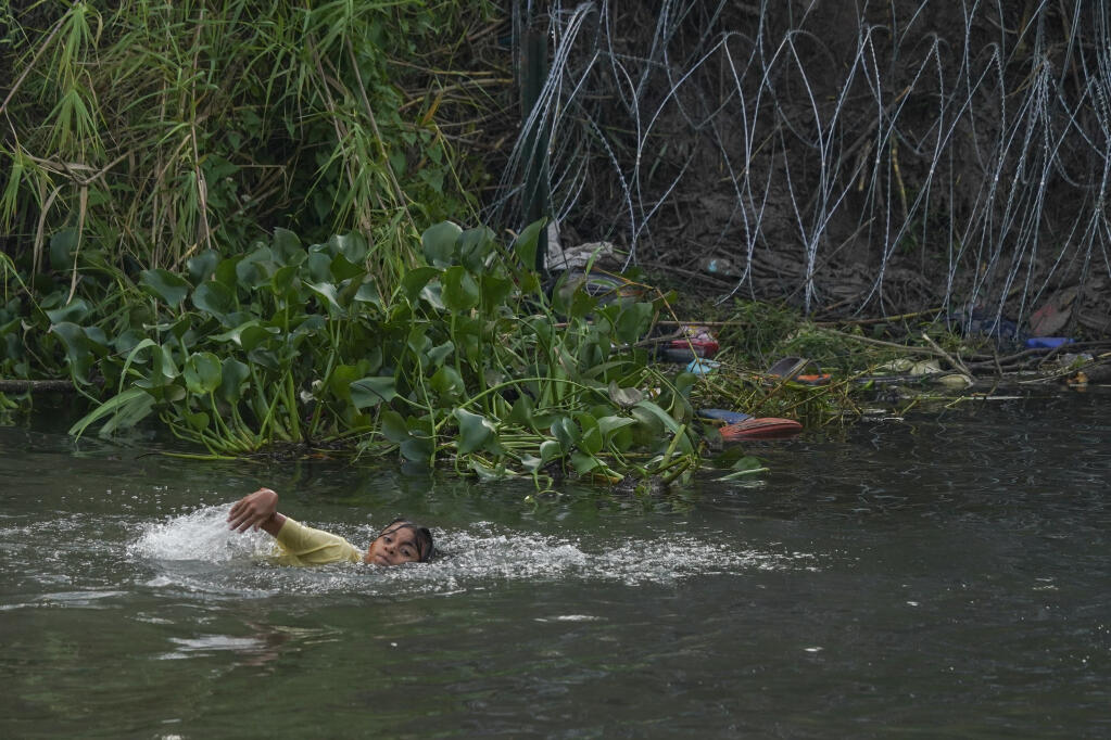 A young migrant swims across the Rio Grande river to the U.S. from Matamoros, Mexico, Wednesday, May 10, 2023. The U.S on May 11 will begin denying asylum to migrants who show up at the U.S.-Mexico border without first applying online or seeking protection in a country they passed through, according to a new rule released May 10. (AP Photo/Fernando Llano)